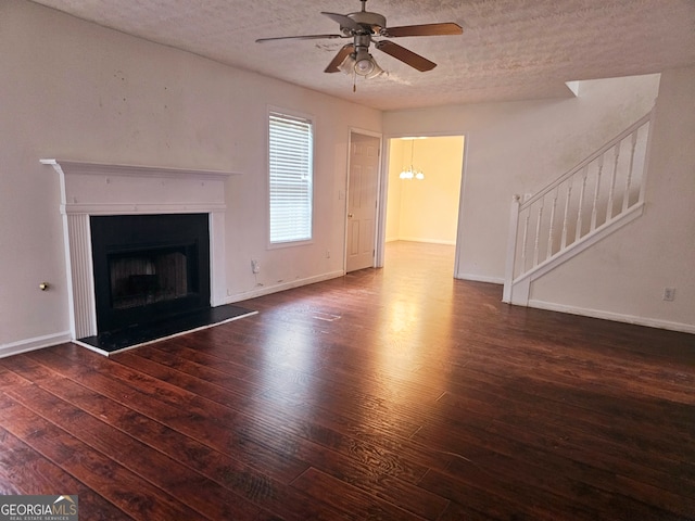 unfurnished living room with ceiling fan with notable chandelier, a textured ceiling, and dark hardwood / wood-style floors