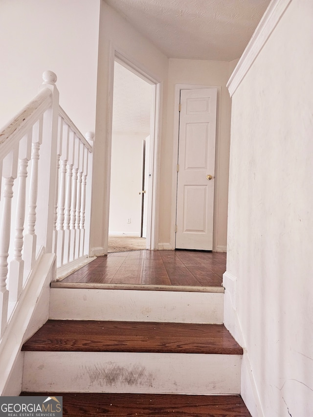 stairs featuring hardwood / wood-style floors and a textured ceiling