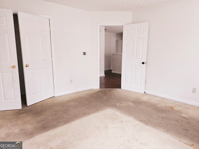 unfurnished bedroom featuring dark colored carpet and a textured ceiling