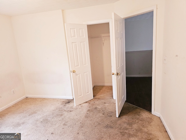 unfurnished bedroom with light carpet and a closet