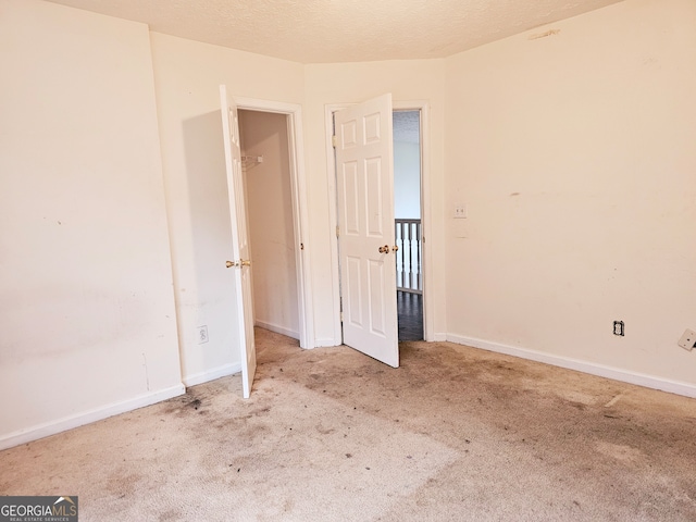 spare room featuring a textured ceiling and light colored carpet