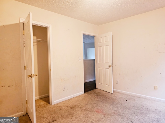 unfurnished bedroom featuring light carpet, a textured ceiling, and a closet