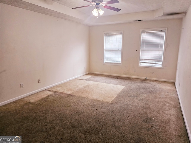 unfurnished room with a tray ceiling, ceiling fan, and carpet floors