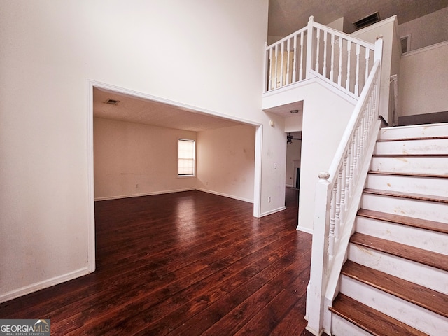 stairway with hardwood / wood-style floors and a high ceiling