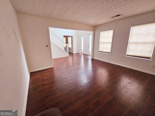 empty room featuring dark hardwood / wood-style flooring and a textured ceiling