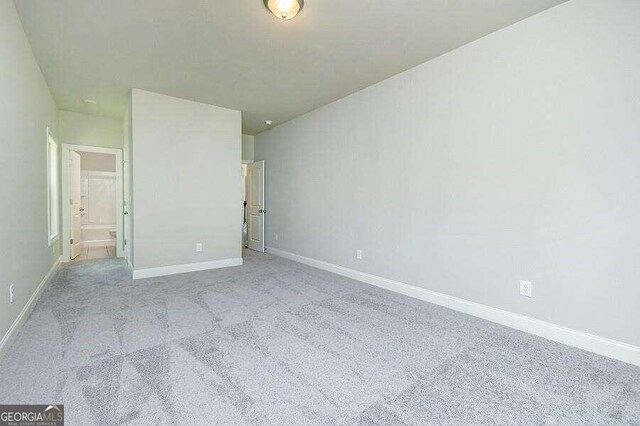 unfurnished bedroom featuring ensuite bathroom and light carpet