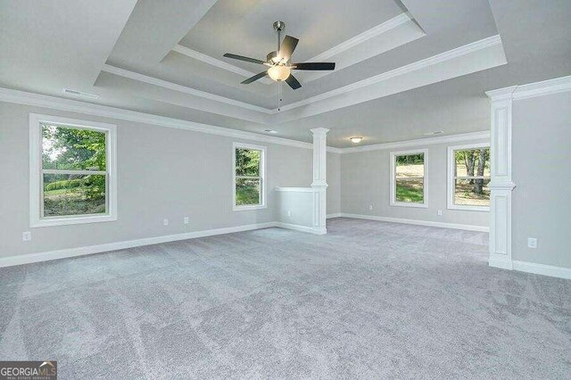 carpeted spare room featuring ornate columns, ornamental molding, ceiling fan, and a tray ceiling