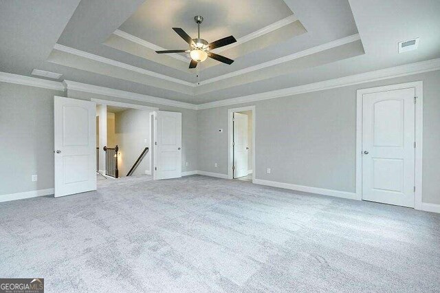 spare room with crown molding, light colored carpet, ceiling fan, and a tray ceiling