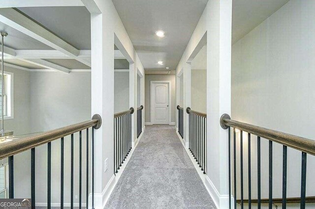 corridor featuring beamed ceiling, coffered ceiling, and carpet flooring