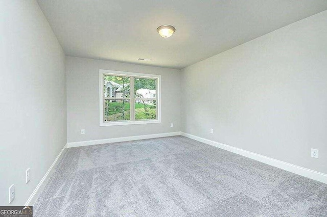 spare room featuring baseboards, visible vents, and carpet