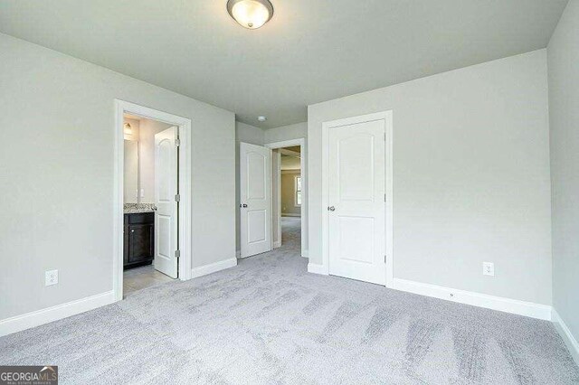 unfurnished bedroom with light carpet and ensuite bath