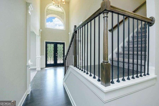 entrance foyer featuring a towering ceiling, a chandelier, dark hardwood / wood-style flooring, and french doors