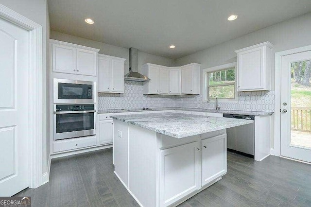 kitchen with dark wood-style flooring, appliances with stainless steel finishes, wall chimney range hood, and white cabinetry