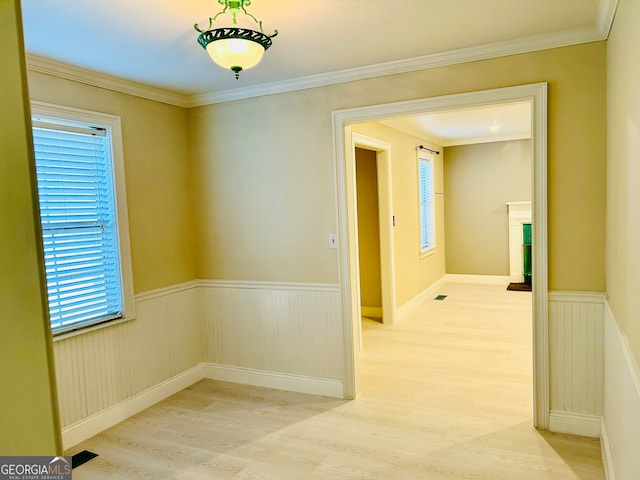 empty room with light wood-type flooring and crown molding