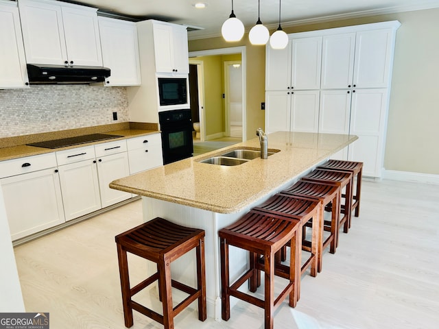 kitchen featuring extractor fan, black appliances, sink, a center island with sink, and hanging light fixtures