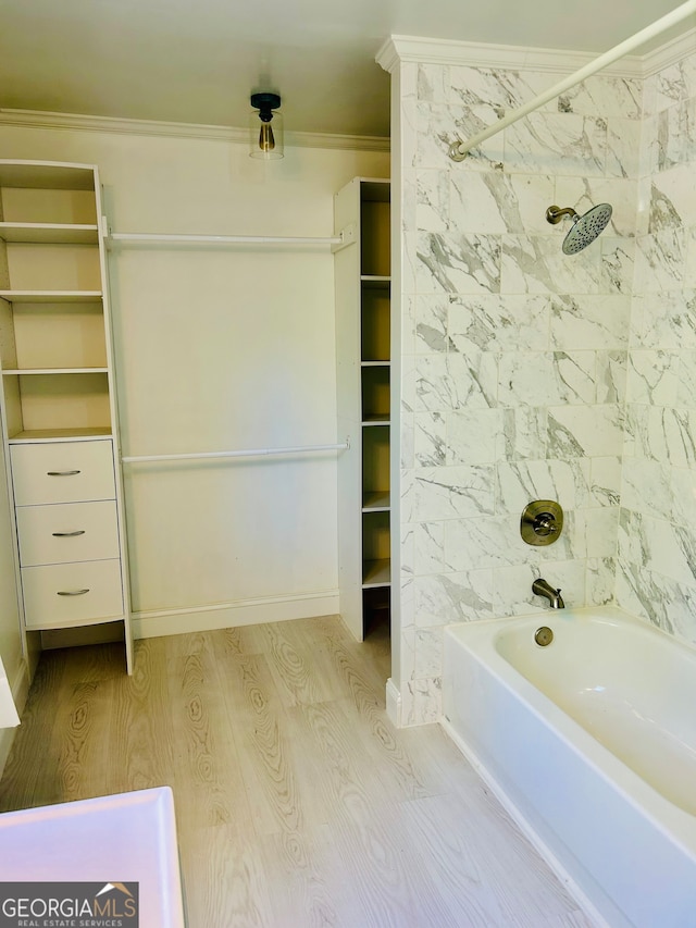 bathroom with hardwood / wood-style floors, crown molding, and tiled shower / bath