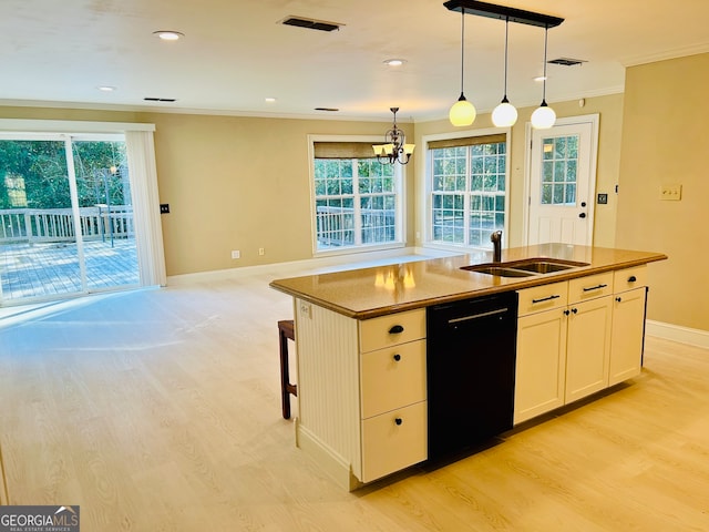 kitchen featuring decorative light fixtures, a healthy amount of sunlight, black dishwasher, and an island with sink