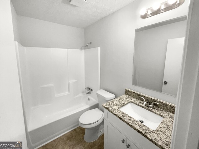 full bathroom featuring vanity, a textured ceiling, toilet, and shower / washtub combination