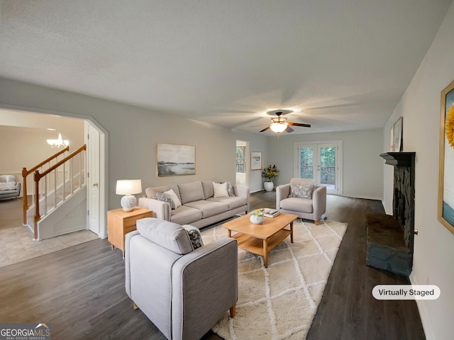 living room featuring hardwood / wood-style floors, ceiling fan with notable chandelier, and a textured ceiling