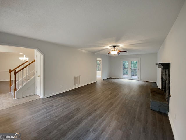 unfurnished living room with french doors, ceiling fan with notable chandelier, dark hardwood / wood-style floors, and a textured ceiling