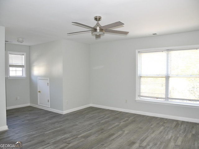 empty room featuring plenty of natural light, ceiling fan, and dark hardwood / wood-style flooring