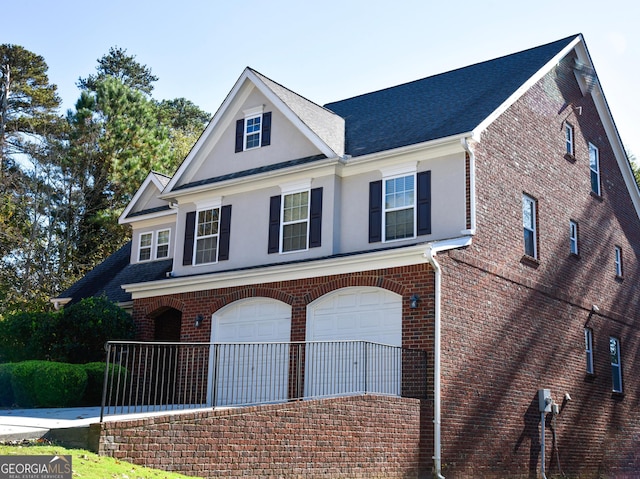 view of front of house with brick siding, stucco siding, driveway, and a garage