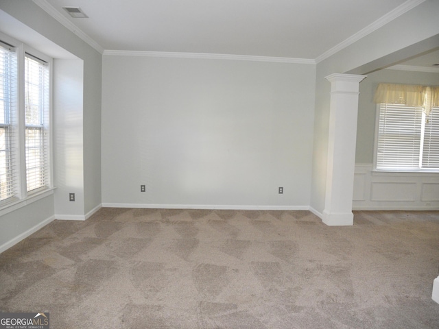 spare room featuring light carpet, decorative columns, and crown molding