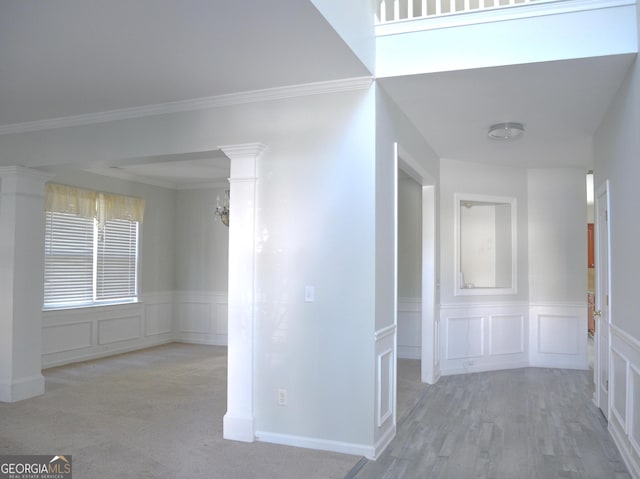 hall featuring light colored carpet, ornate columns, and ornamental molding