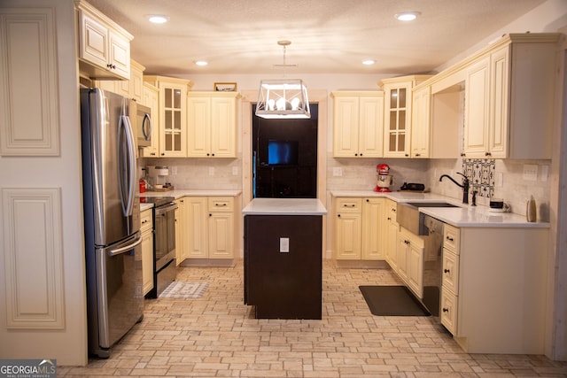 kitchen with a kitchen island, appliances with stainless steel finishes, pendant lighting, sink, and cream cabinets