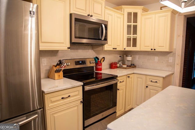 kitchen with cream cabinets, decorative backsplash, and stainless steel appliances