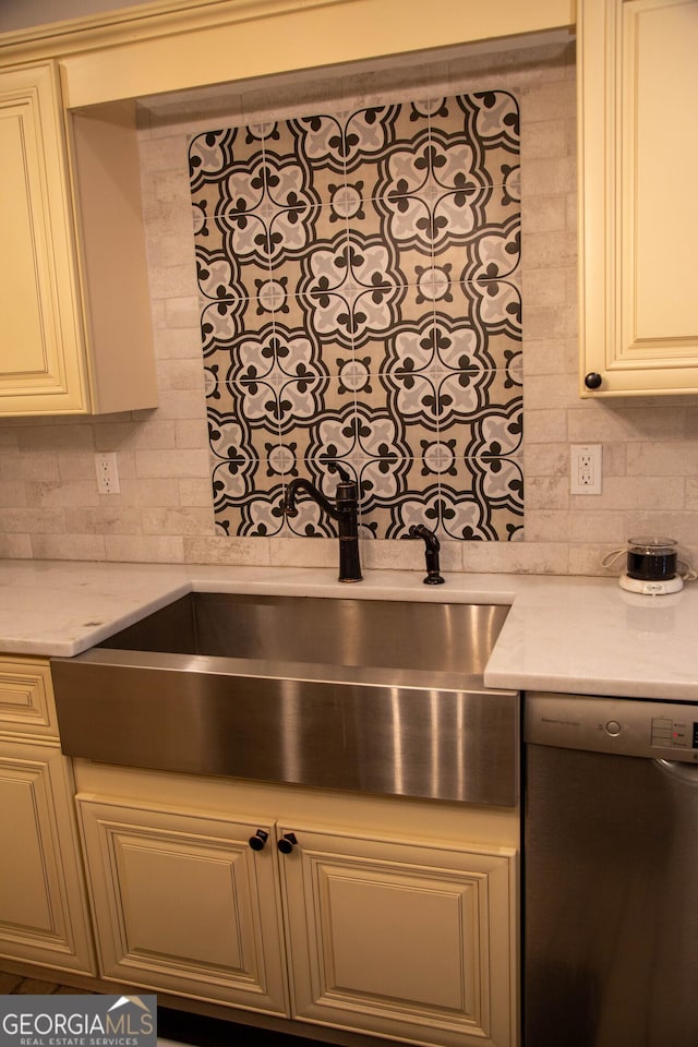 kitchen featuring light stone counters, stainless steel dishwasher, sink, and decorative backsplash