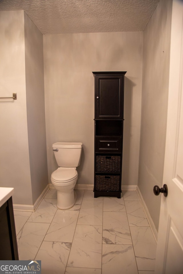 bathroom featuring vanity, a textured ceiling, and toilet