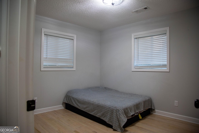 bedroom with a textured ceiling and light hardwood / wood-style flooring