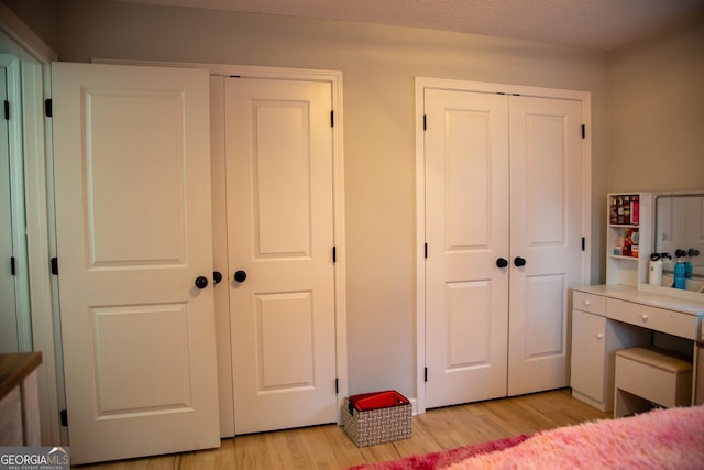 bedroom with multiple closets and light hardwood / wood-style floors