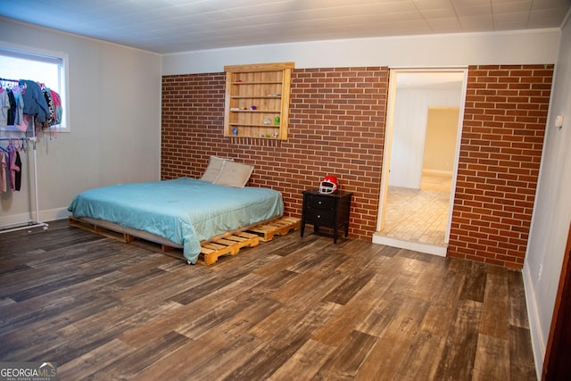 bedroom featuring crown molding, brick wall, and dark hardwood / wood-style flooring