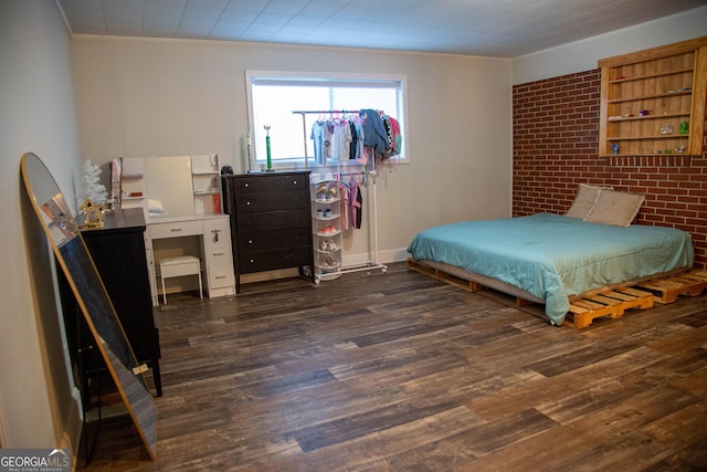 bedroom featuring dark wood-type flooring, ornamental molding, and brick wall