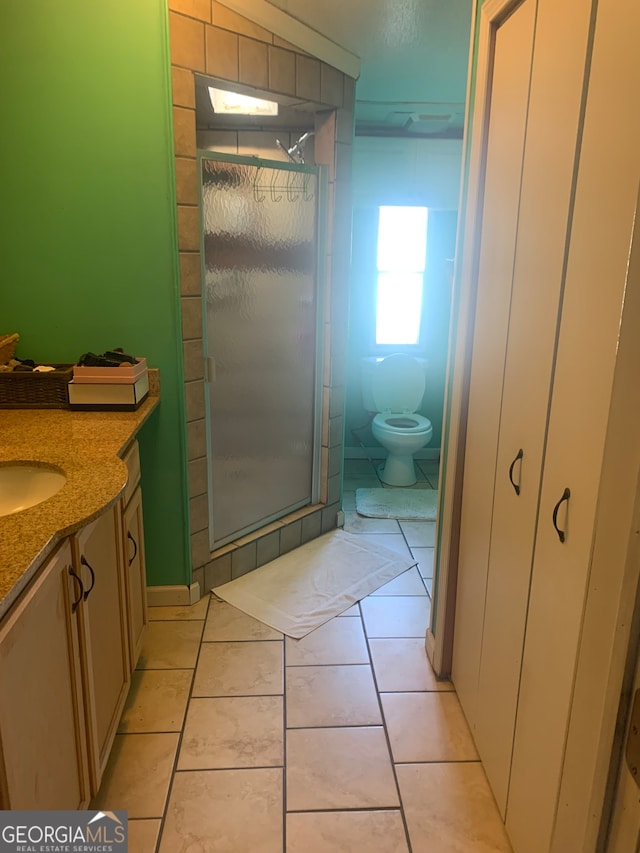 bathroom featuring tile patterned flooring, vanity, toilet, and an enclosed shower