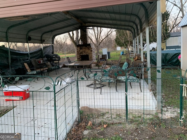 view of patio with an outdoor stone fireplace, a carport, and a grill