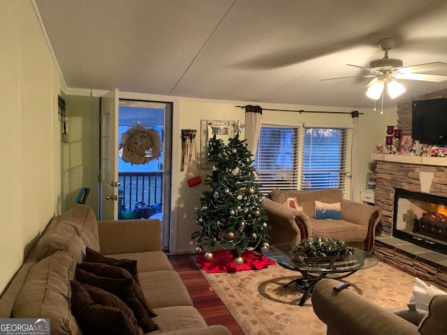 living room with hardwood / wood-style flooring, ceiling fan, and a stone fireplace