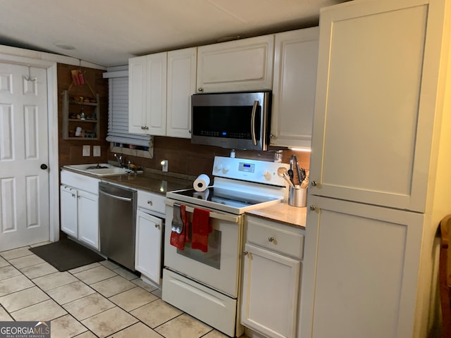 kitchen with light tile patterned floors, white cabinetry, sink, and appliances with stainless steel finishes