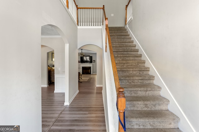 staircase with hardwood / wood-style floors and a high ceiling