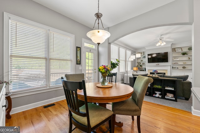 dining room featuring ornamental molding, light wood-type flooring, ceiling fan, and a healthy amount of sunlight