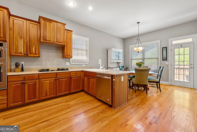 kitchen with kitchen peninsula, stainless steel dishwasher, a healthy amount of sunlight, and sink