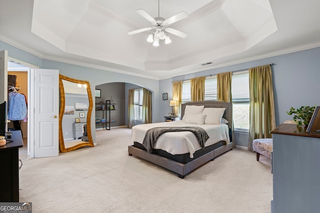 bedroom with a raised ceiling, ceiling fan, carpet floors, and ornamental molding