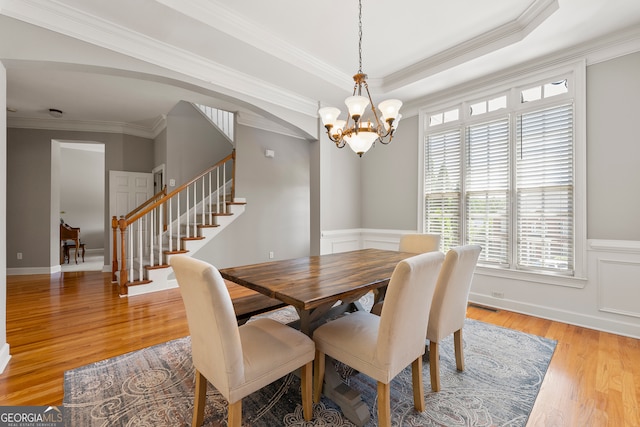 dining room with a tray ceiling, a chandelier, ornamental molding, and light wood-type flooring