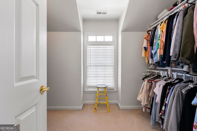 spacious closet with light colored carpet and vaulted ceiling