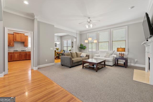 living room featuring ceiling fan, light colored carpet, and ornamental molding