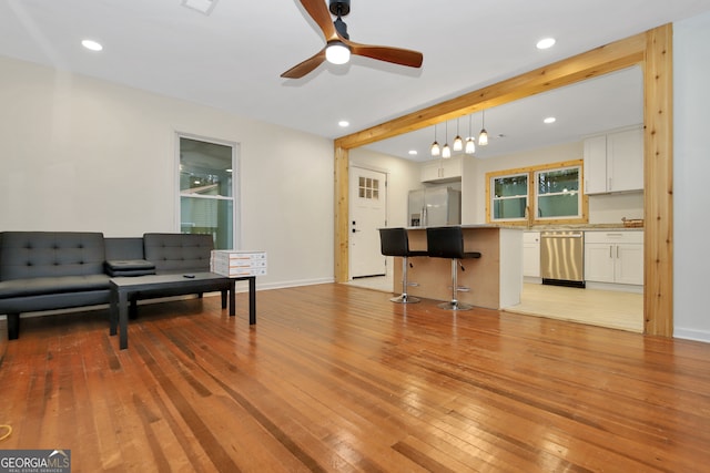 living room featuring ceiling fan, beamed ceiling, and light hardwood / wood-style floors