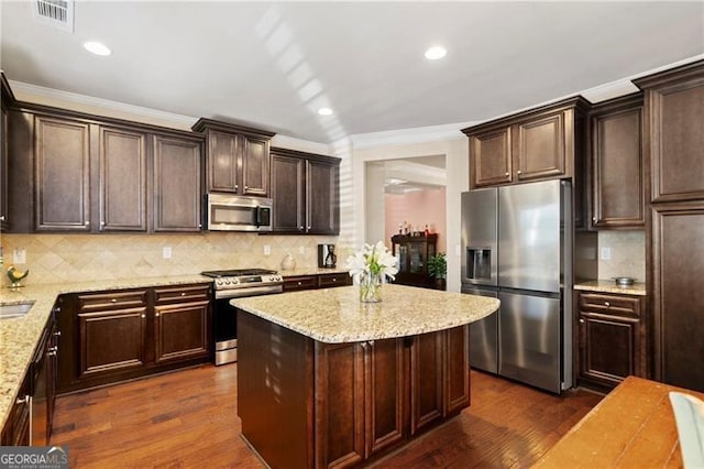 kitchen featuring a center island, dark wood-type flooring, decorative backsplash, light stone countertops, and stainless steel appliances