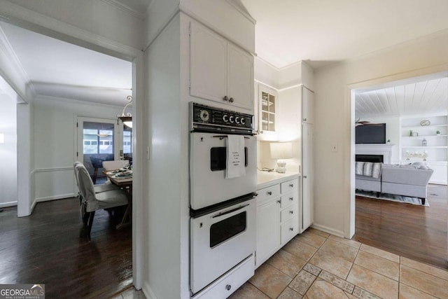 kitchen featuring double oven, light hardwood / wood-style flooring, white cabinets, and ornamental molding